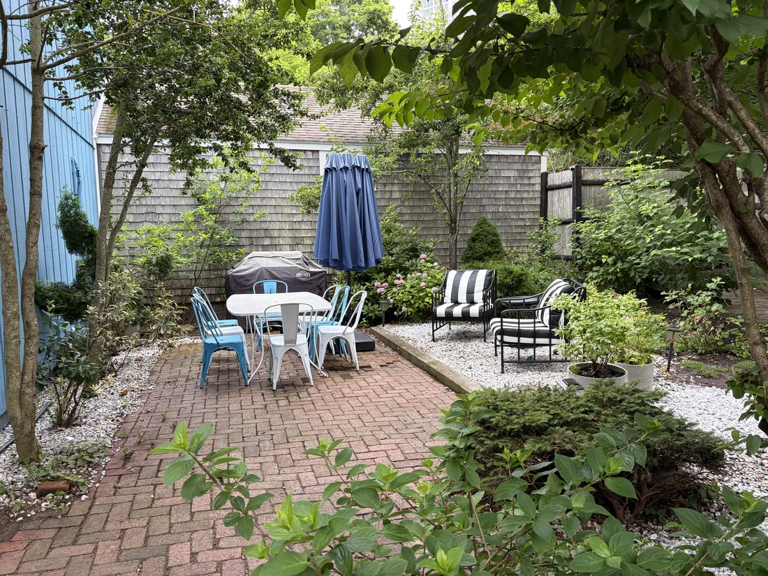 The private garden behind Ptown Perch with mature trees, outdoor dining and lounge chairs